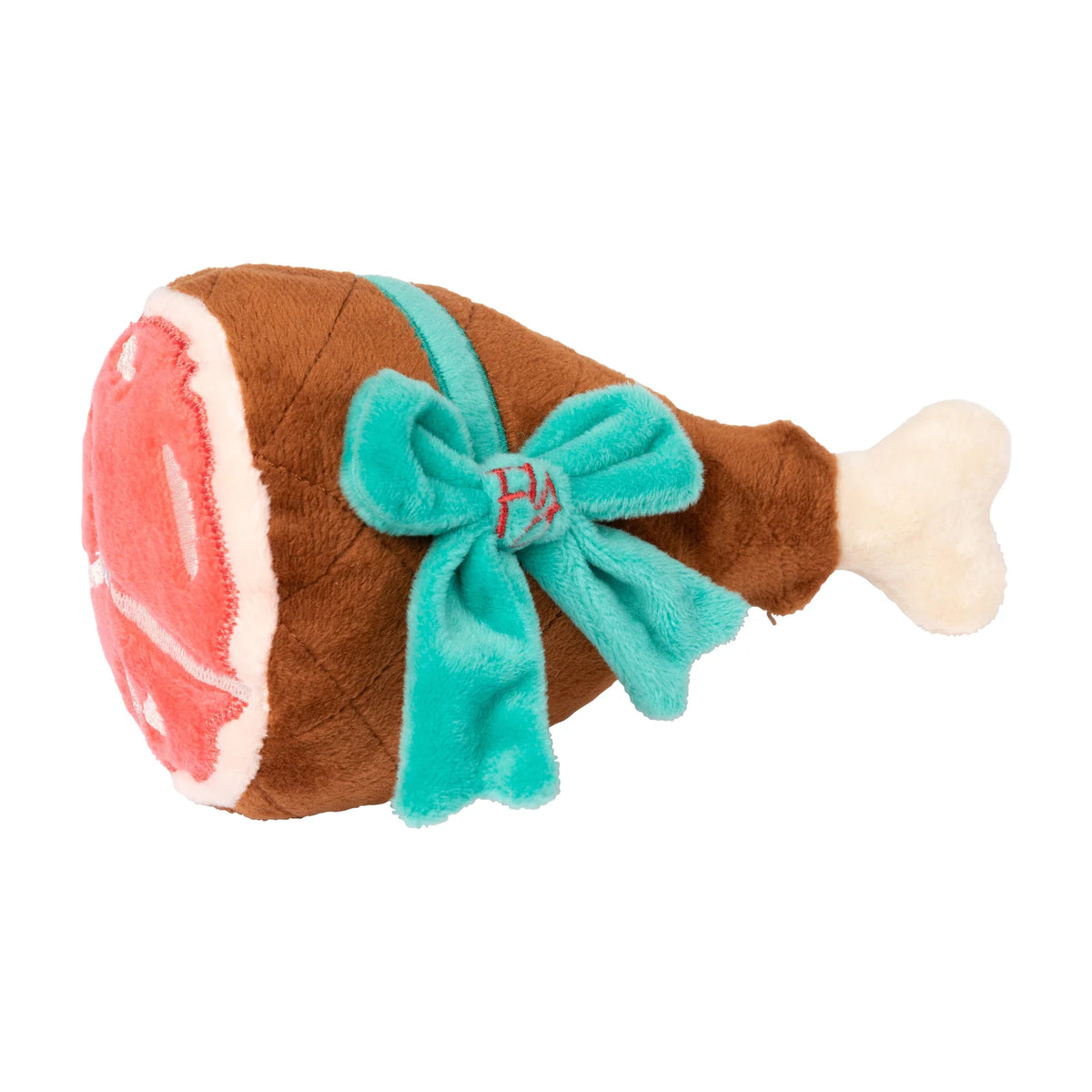 A FuzzYard Humongous Holiday Ham plush Christmas dog toy, with a brown body, pink and white meat section, and a turquoise bow with a small red embroidered monogram.