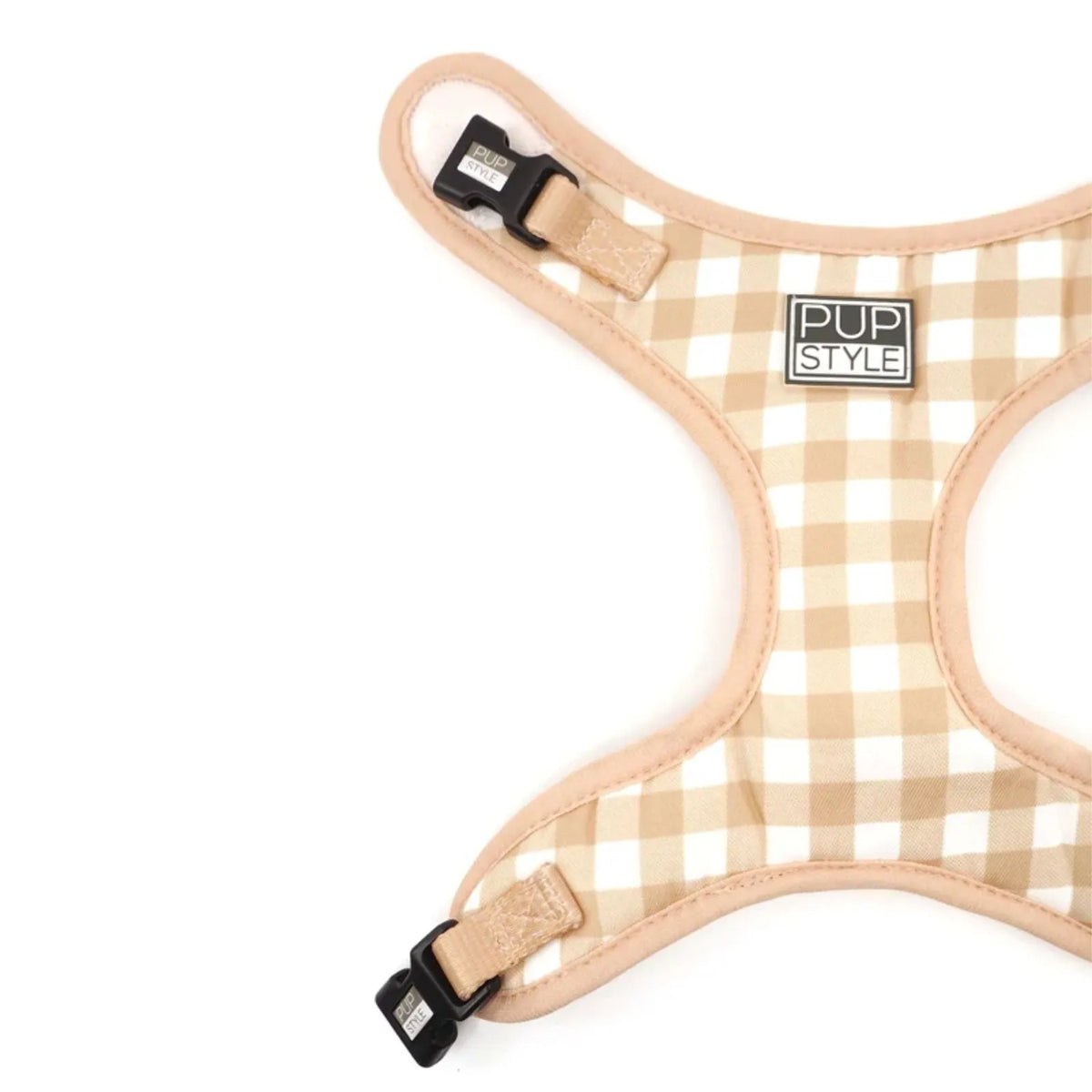 Close-up of a dog harness with a beige and white gingham pattern, tan trim, and black plastic quick-release buckles. A square brand label reading 'PUP STYLE' is stitched on the front.